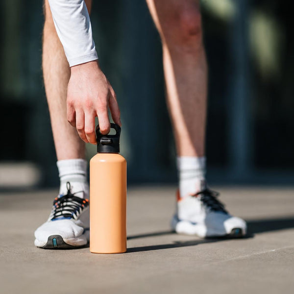 Athlete holding a portable water bottle during an outdoor workout