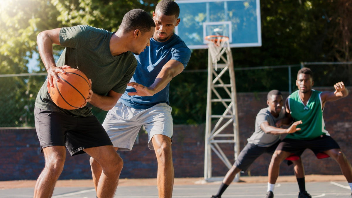 Two men playing a competitive basketball game on an outdoor court