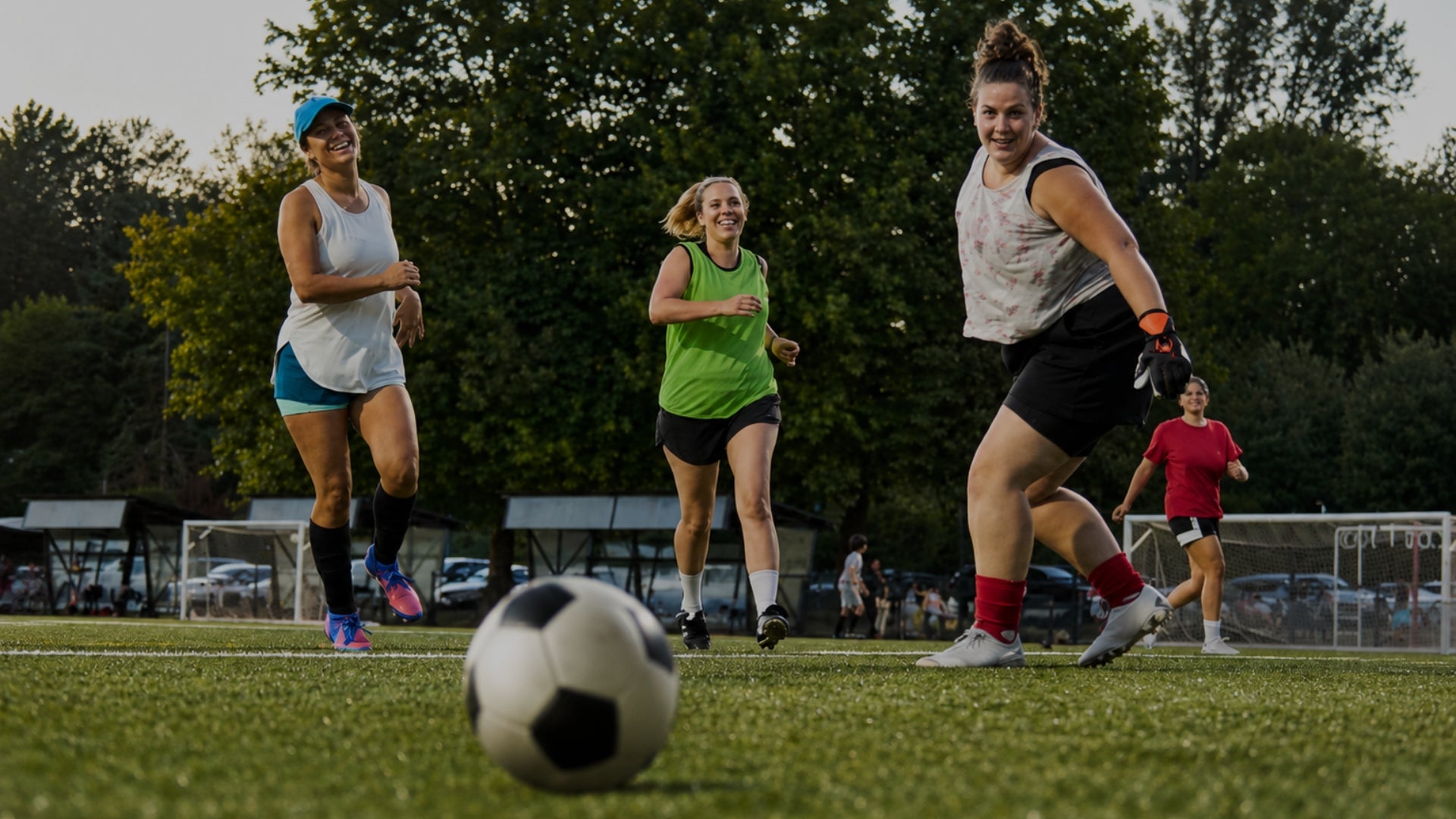 Group of women playing a competitive soccer game on green grass